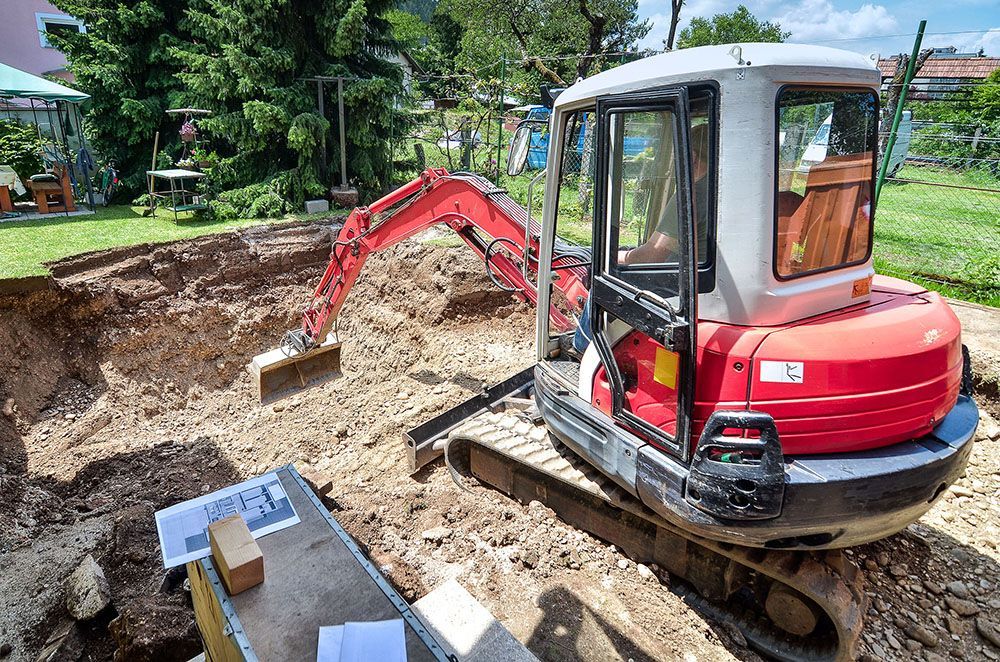 A red and white excavator is digging a hole in the ground.