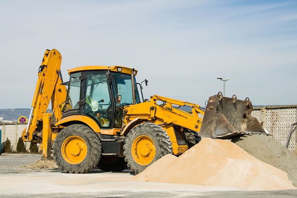 A yellow bulldozer is loading sand into a pile.