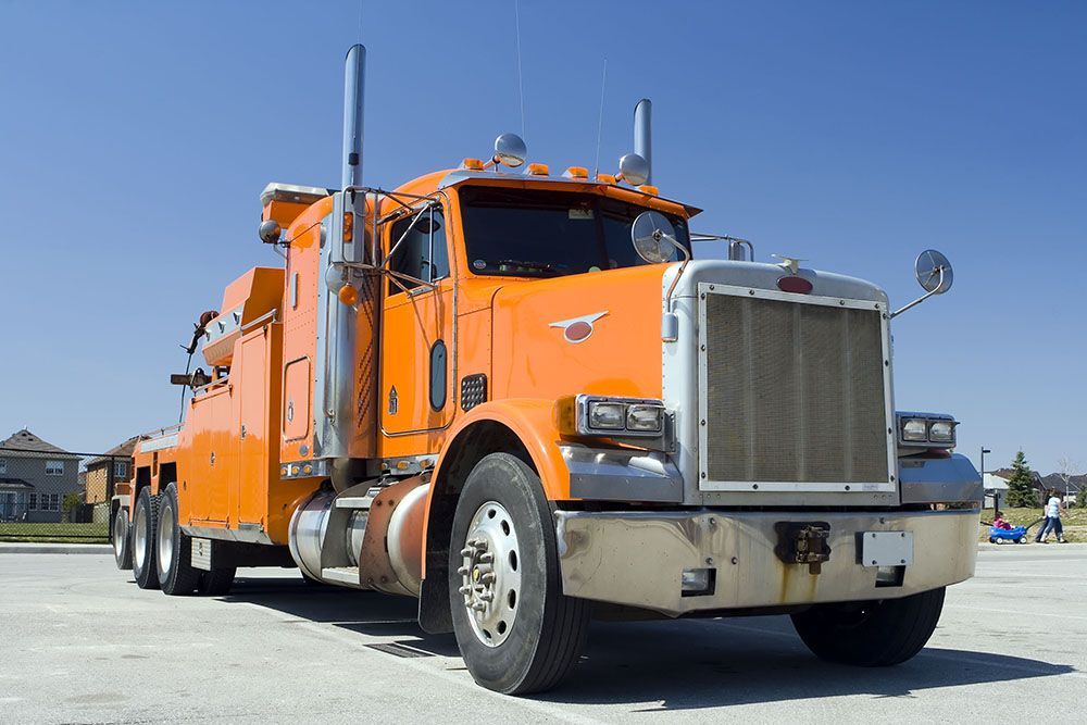 An orange tow truck is parked in a parking lot.