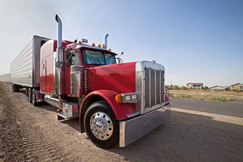 A red semi truck is parked on the side of the road.