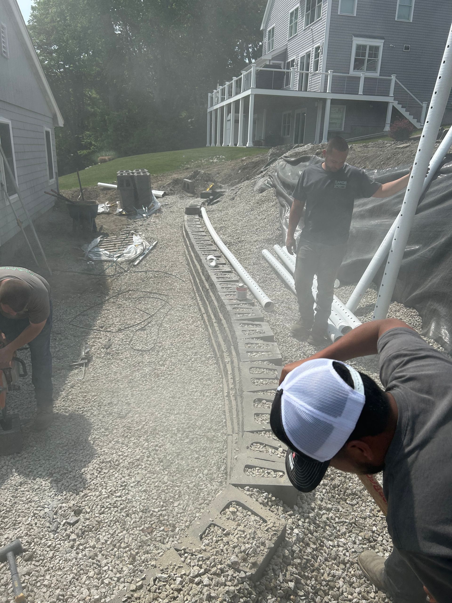 A group of men are working on a gravel driveway in front of a house.