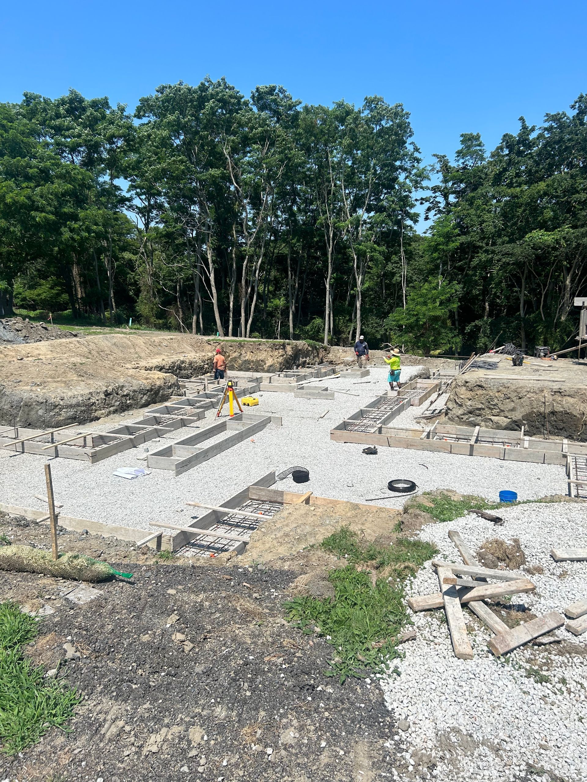 A construction site with a lot of gravel and trees in the background.