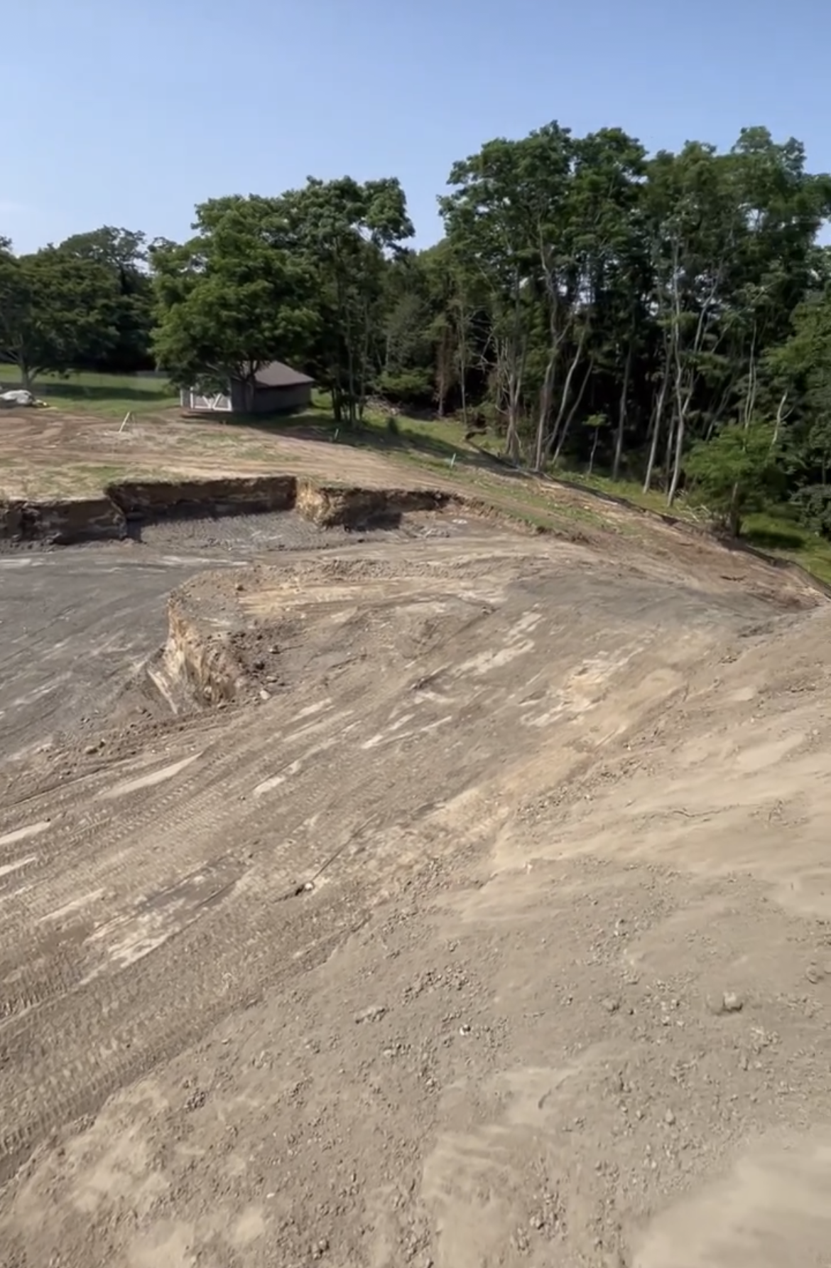 A dirt road going through a park with trees in the background.