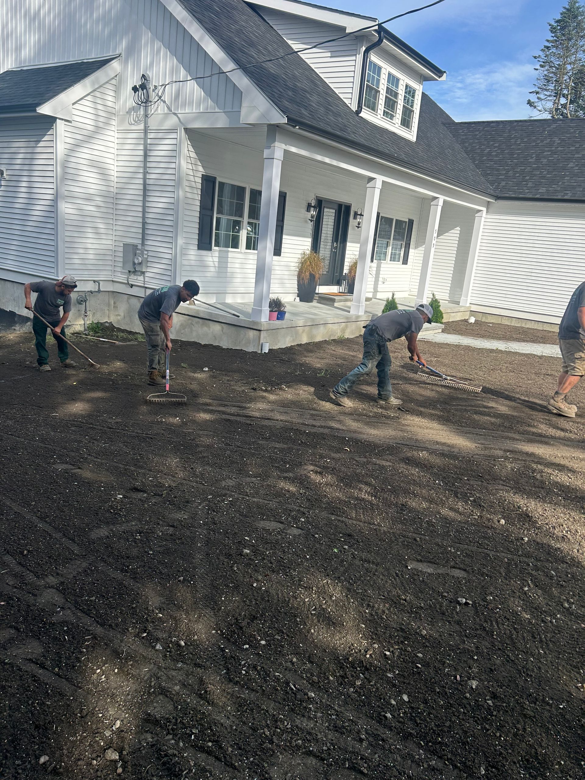 A group of men are digging in the dirt in front of a house.