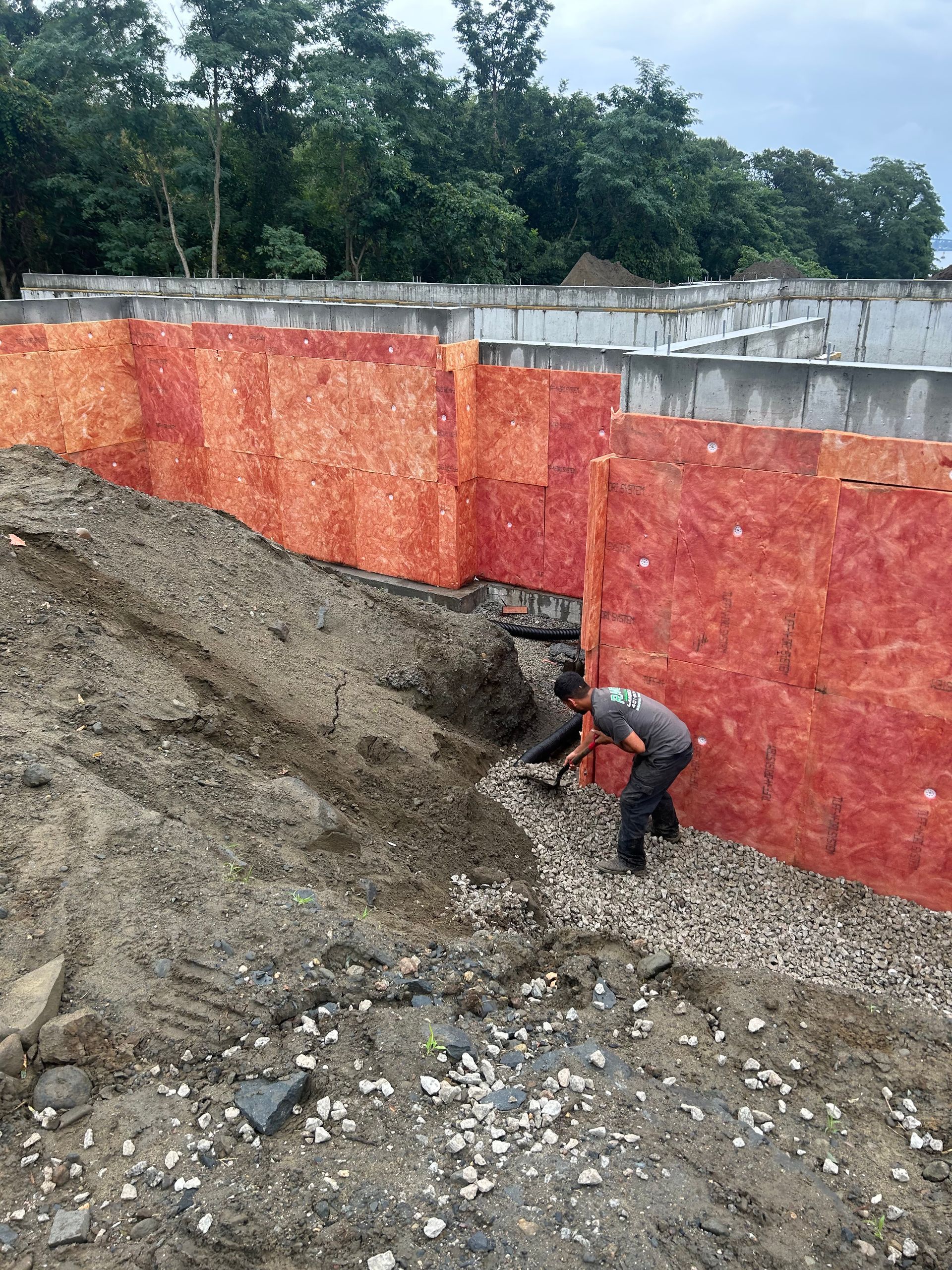 A man is digging in the dirt in front of a wall.