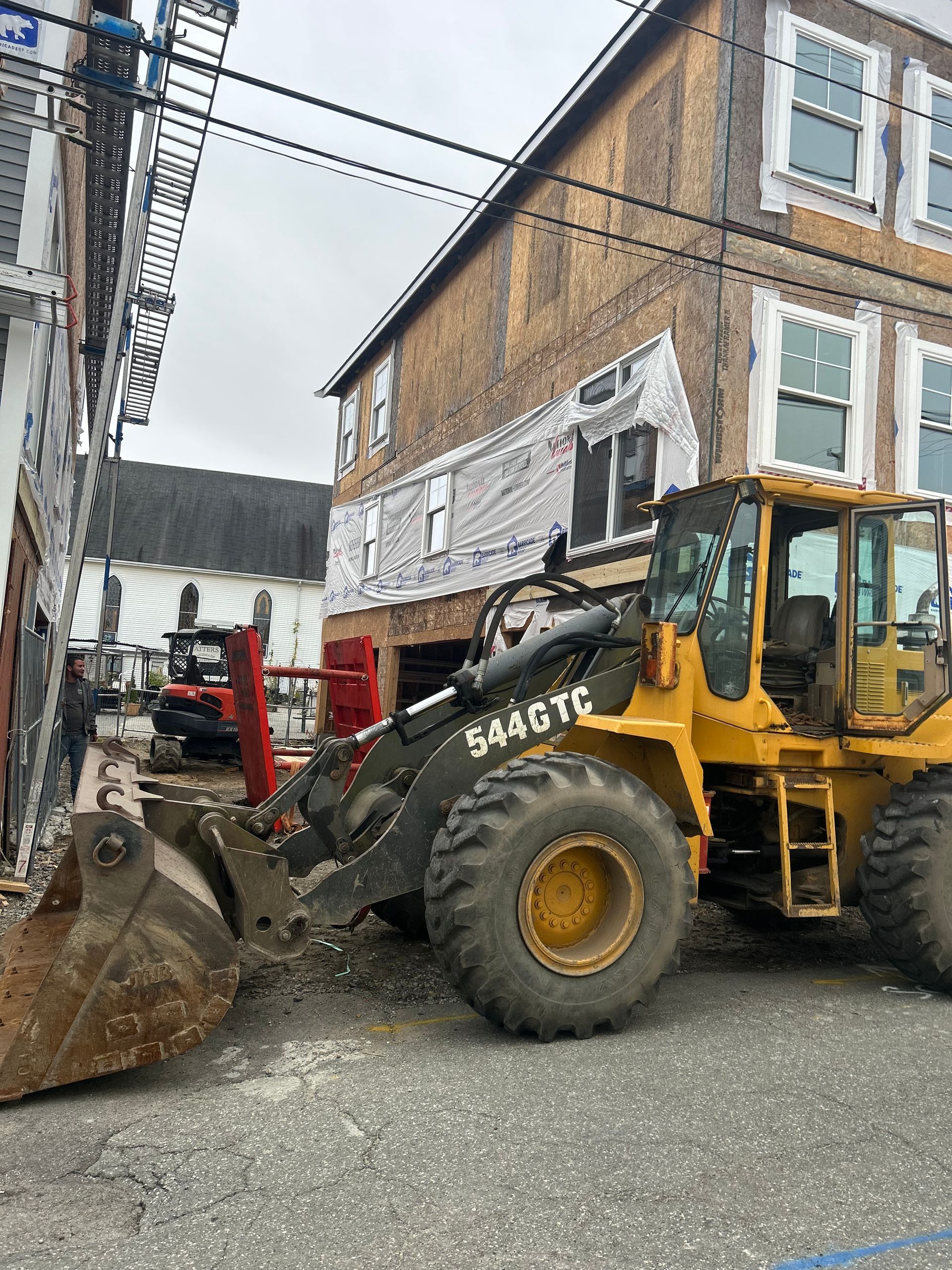 A yellow tractor is parked in front of a building under construction.