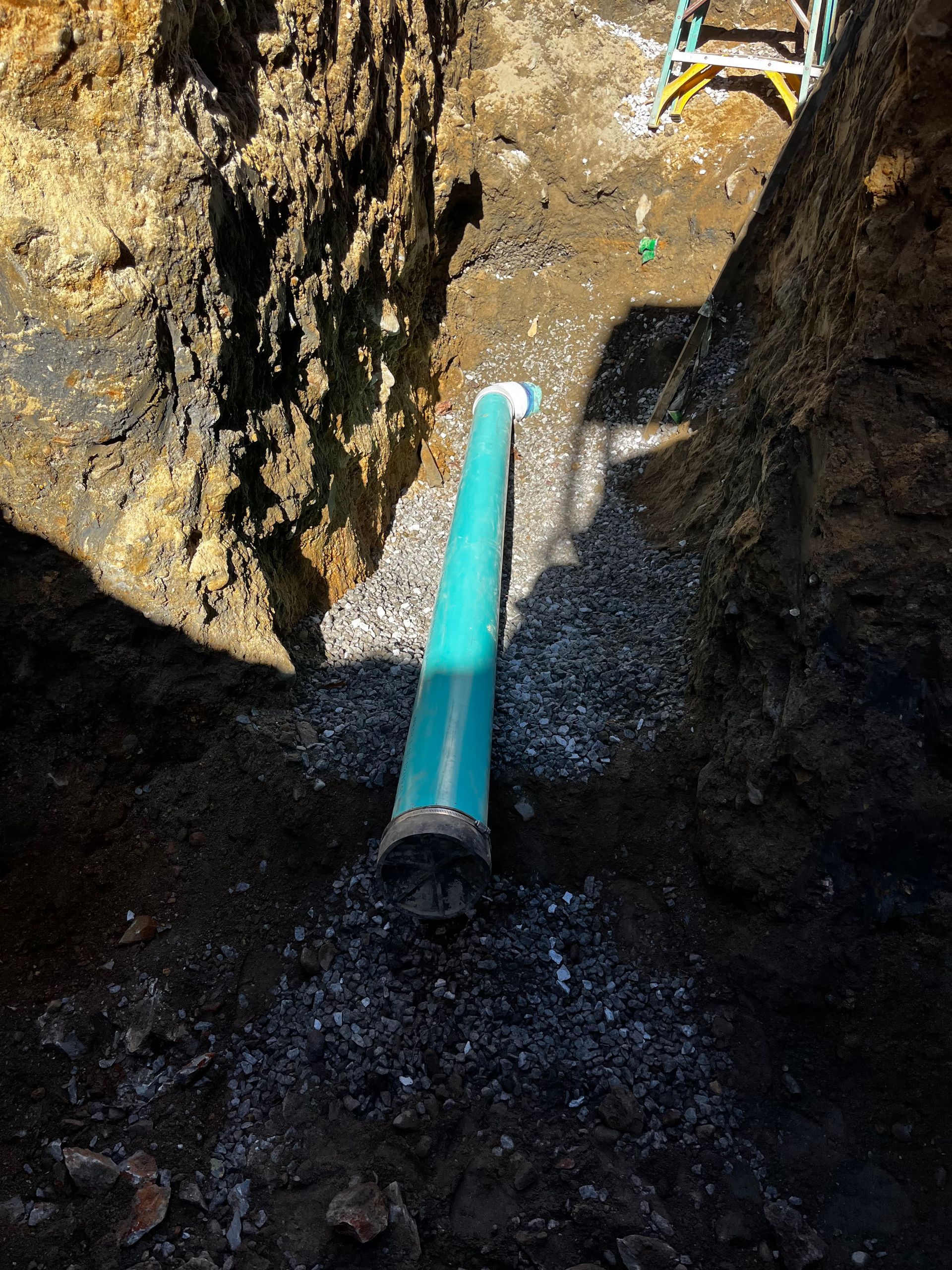 A green pipe is sitting in a hole in the ground.