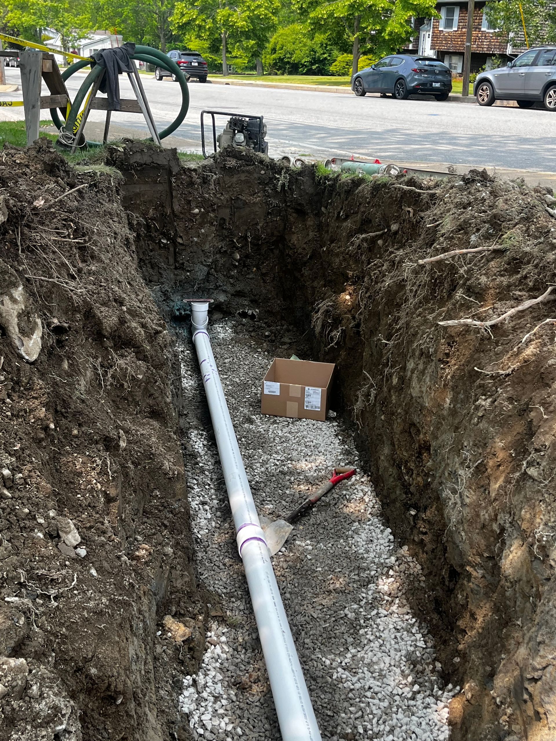A white pipe is being installed in a hole in the ground.