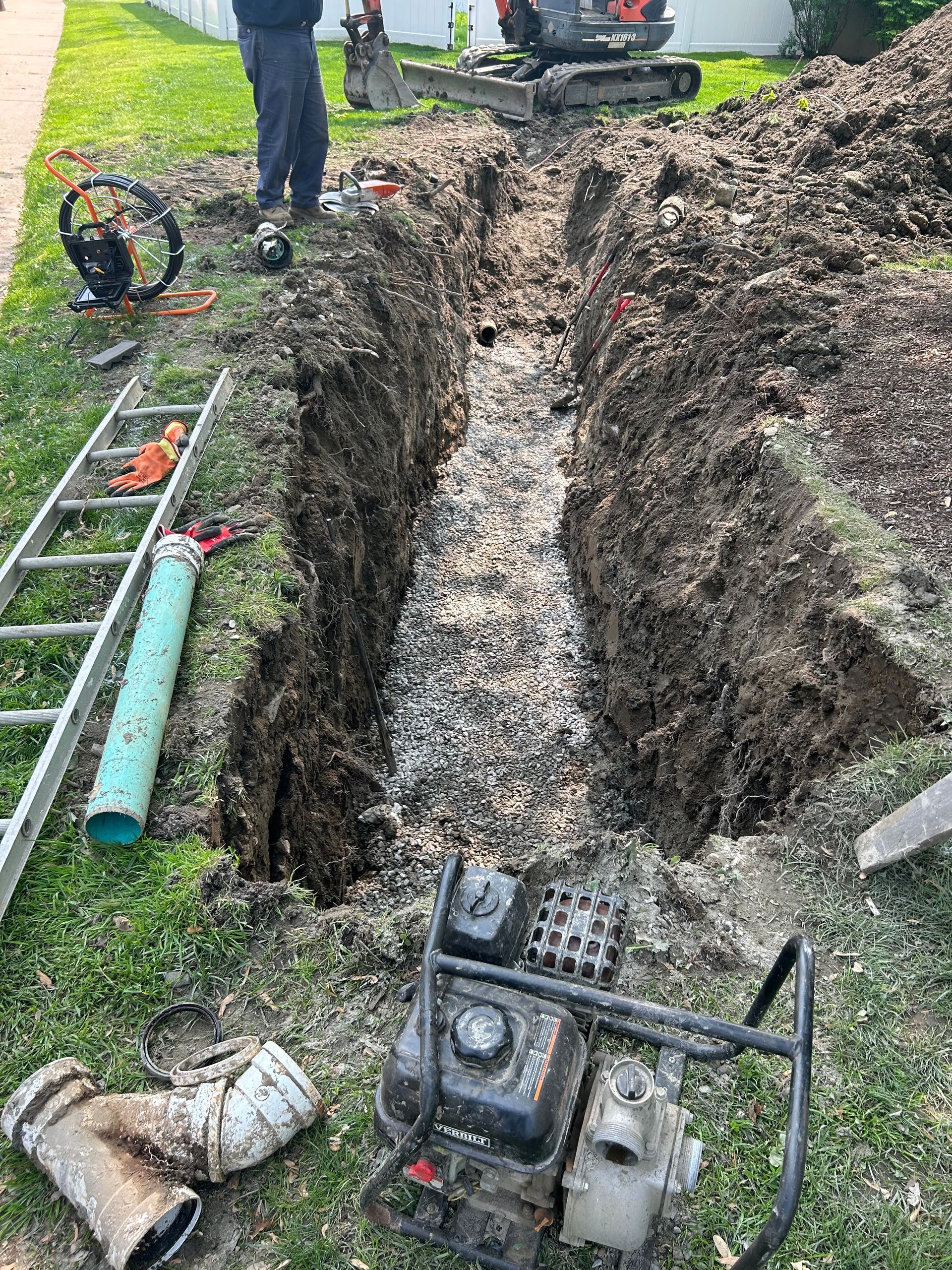 A man is digging a hole in the ground in front of a house.