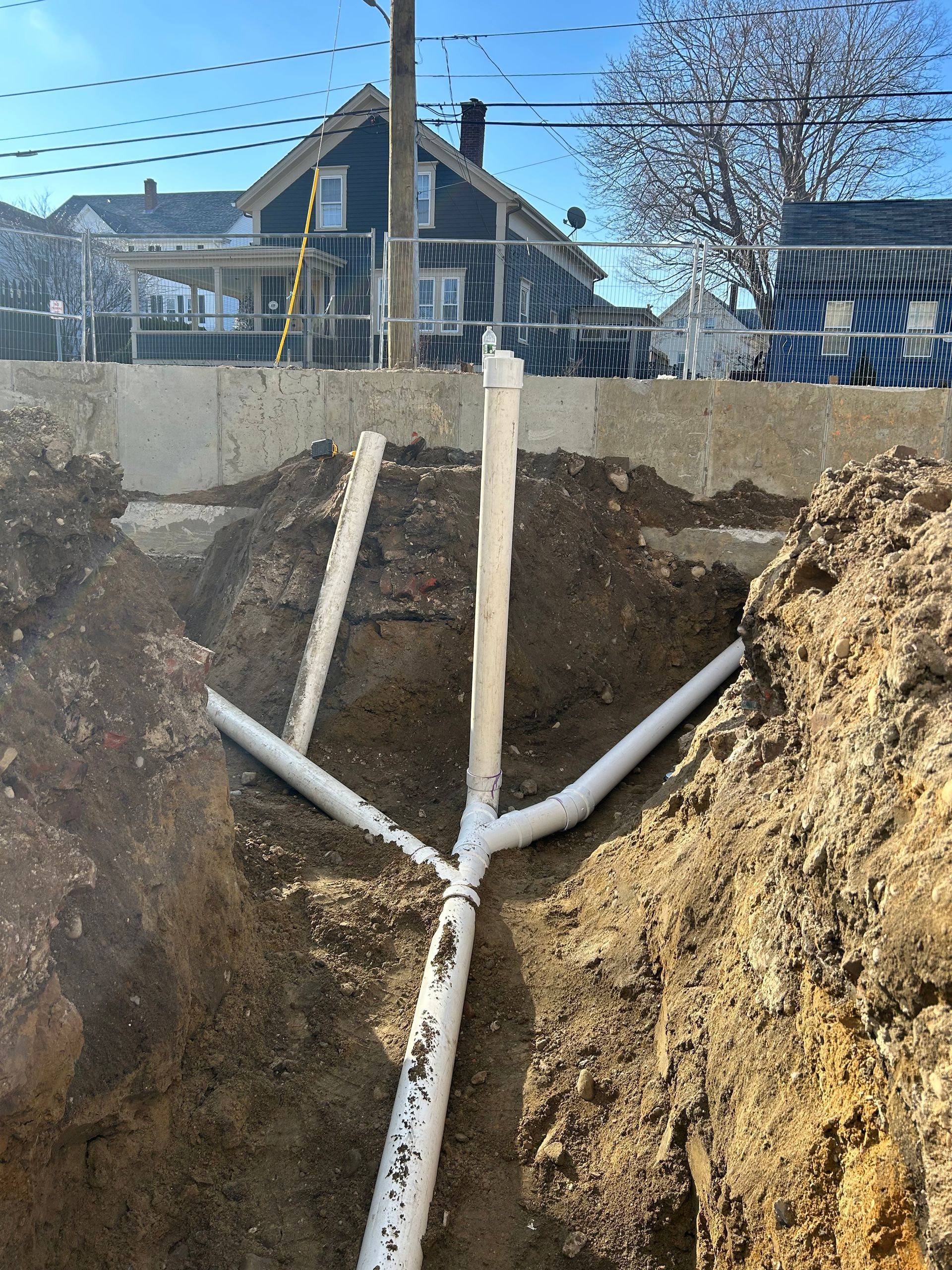 A white pipe is laying in the dirt in front of a house.