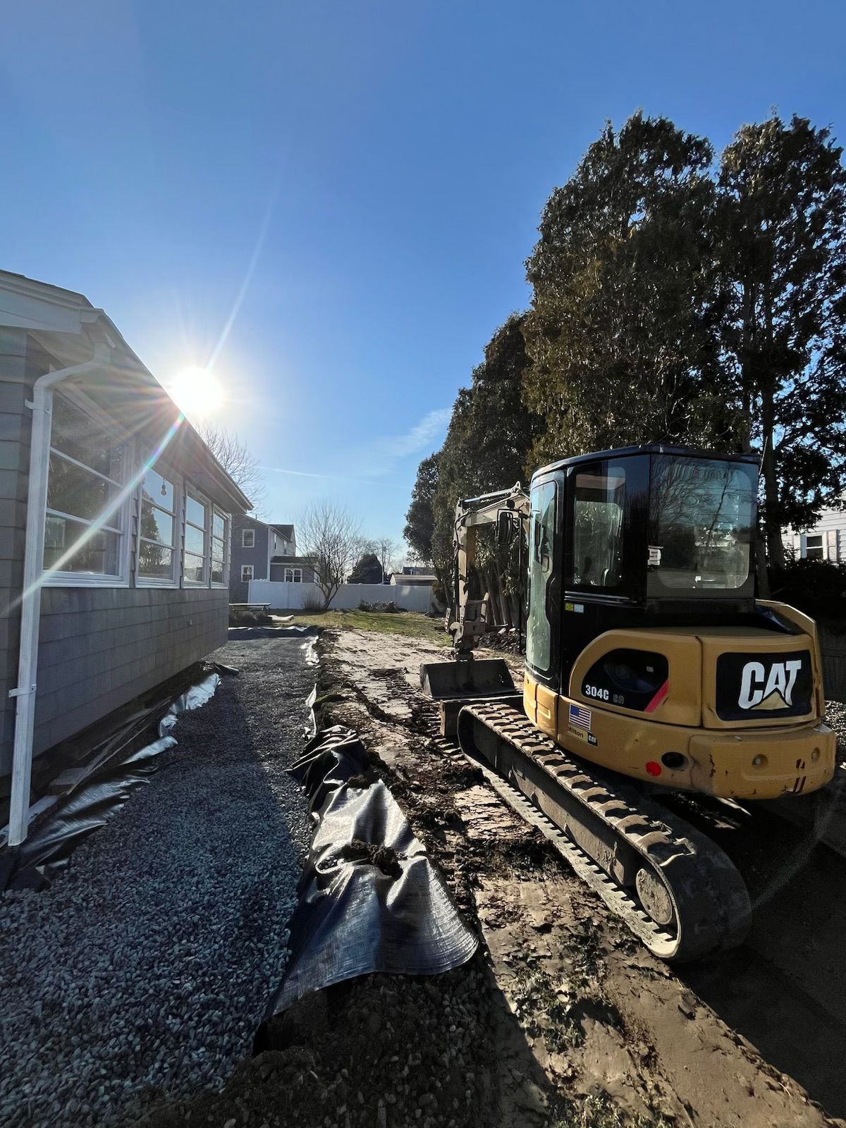 A yellow cat excavator is parked in front of a house.