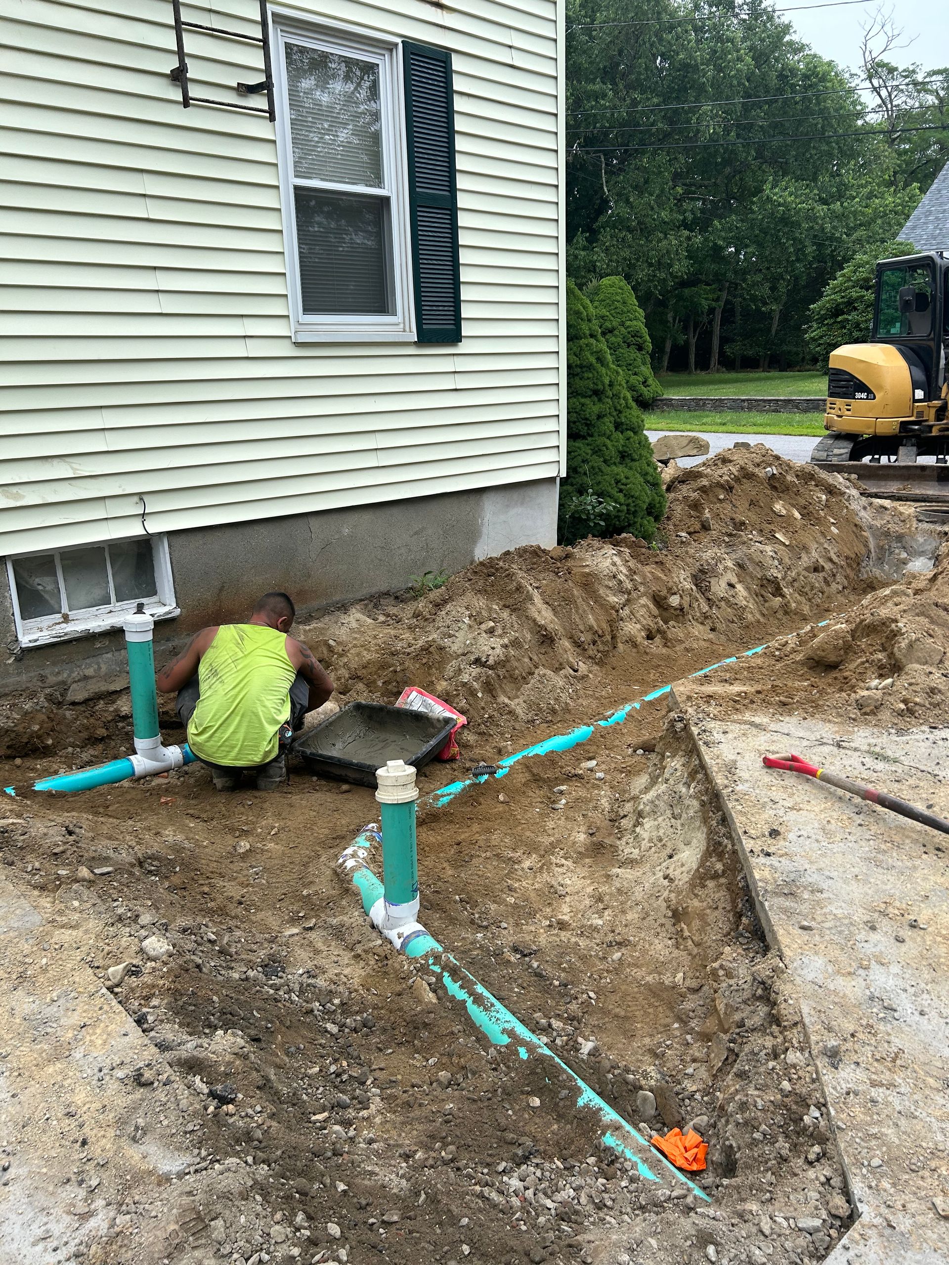A man is kneeling in the dirt in front of a house.