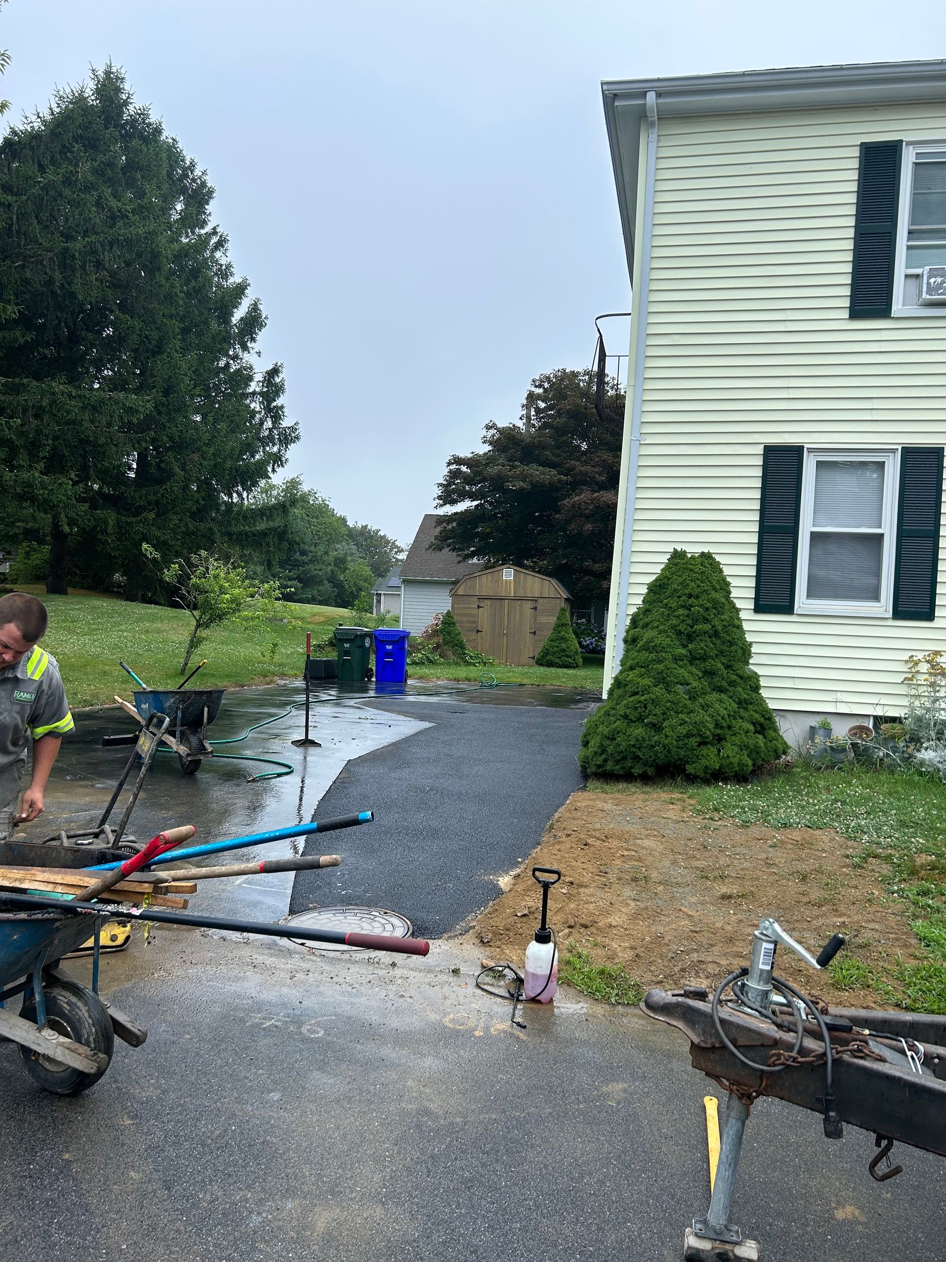 A man is working on a driveway next to a house.