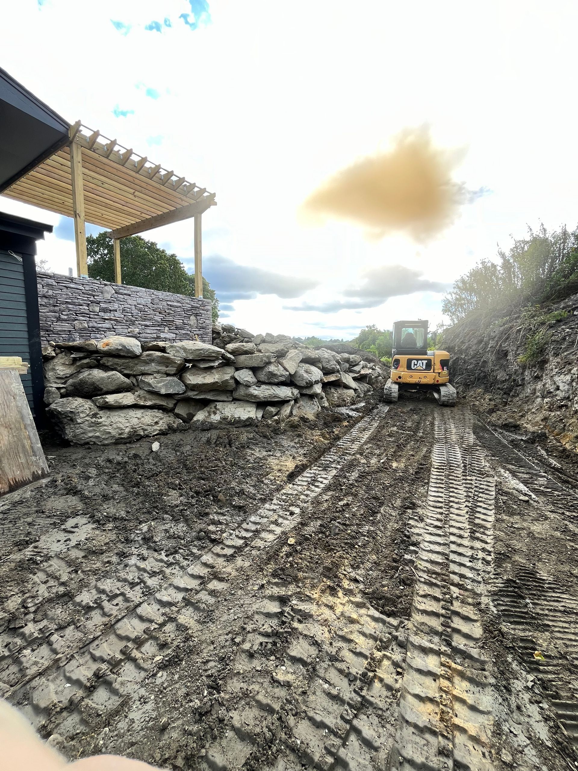 A bulldozer is driving down a dirt road next to a pile of rocks.