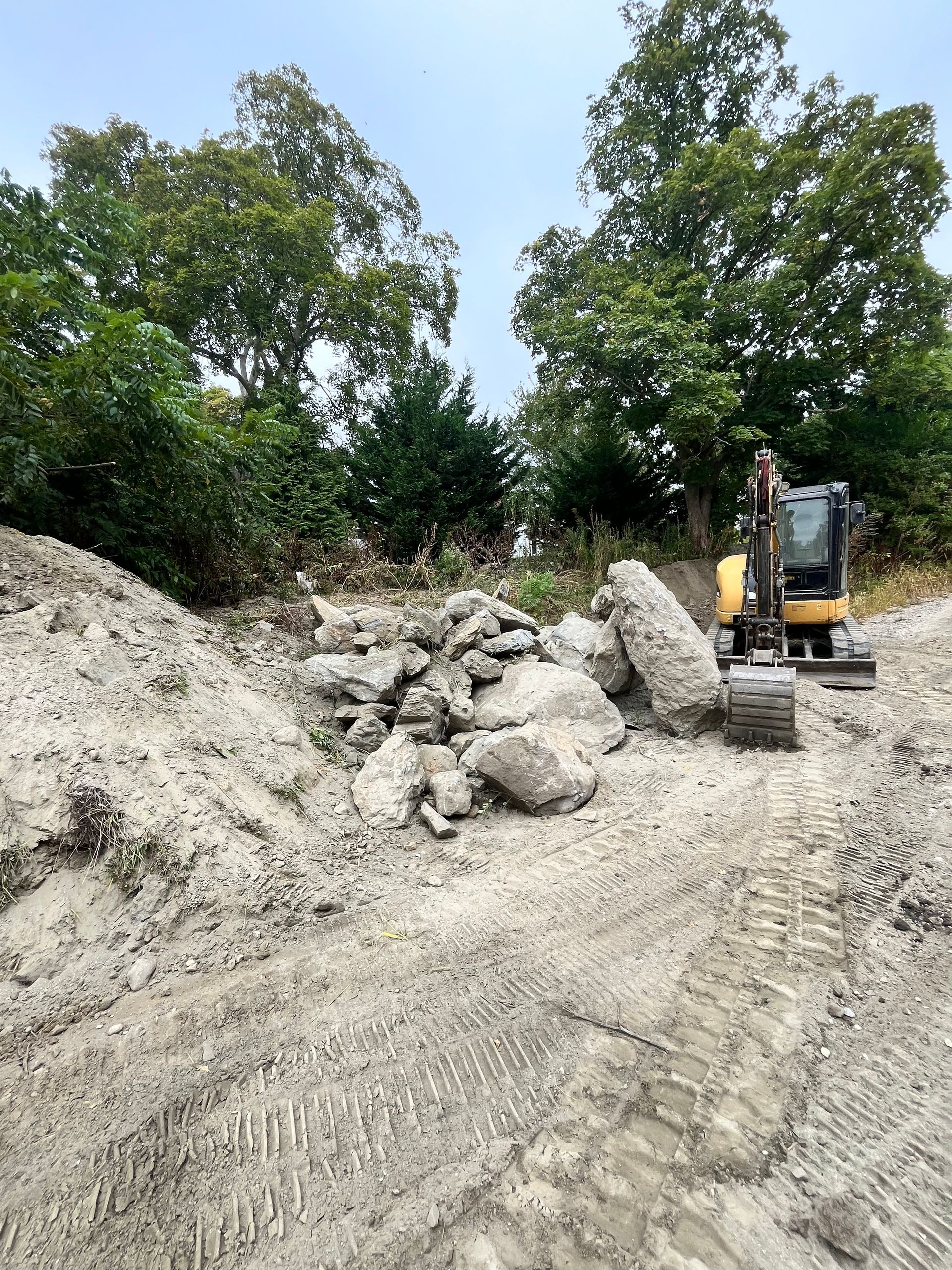 A small excavator is working on a pile of rocks in a dirt field.