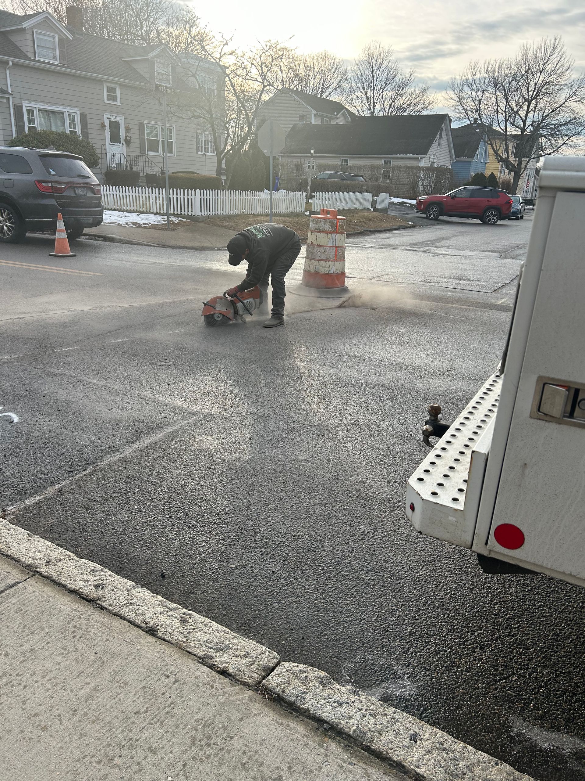 A man is kneeling on the ground in a parking lot next to a truck.