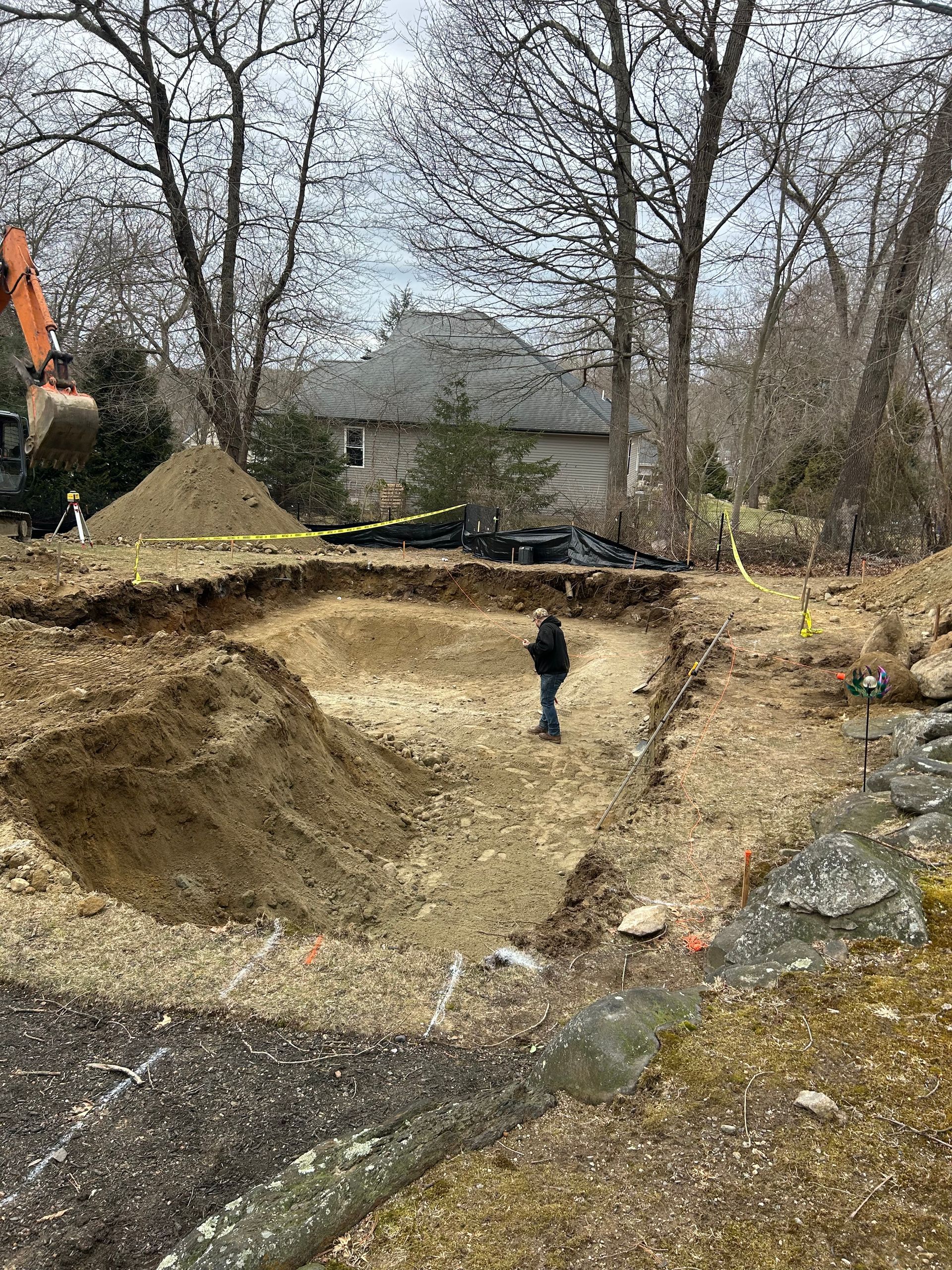 A man is standing in the middle of a dirt field in front of a house.