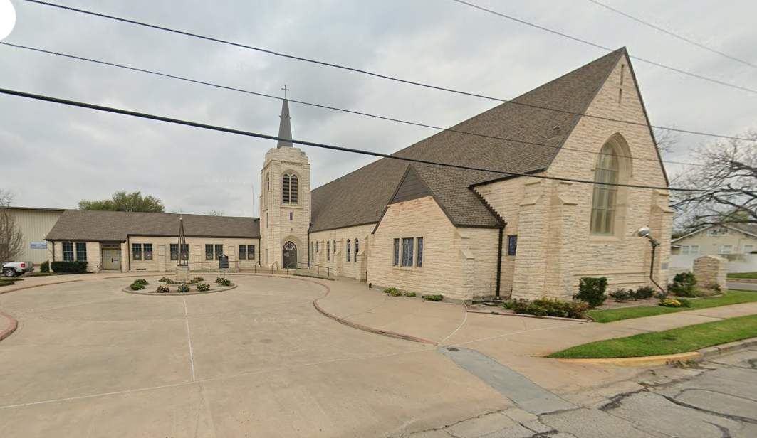 A large brick church with a steeple is surrounded by power lines.