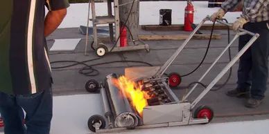 A man is using a machine to burn a piece of paper on a roof.
