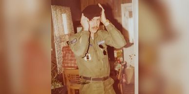 A man in a military uniform is covering his ears with his hands.