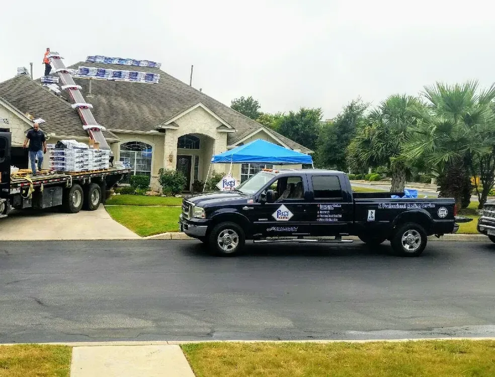 A truck is driving down a street in front of a house