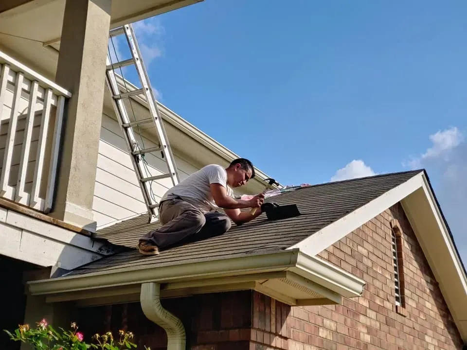 A man is working on the roof of a house.