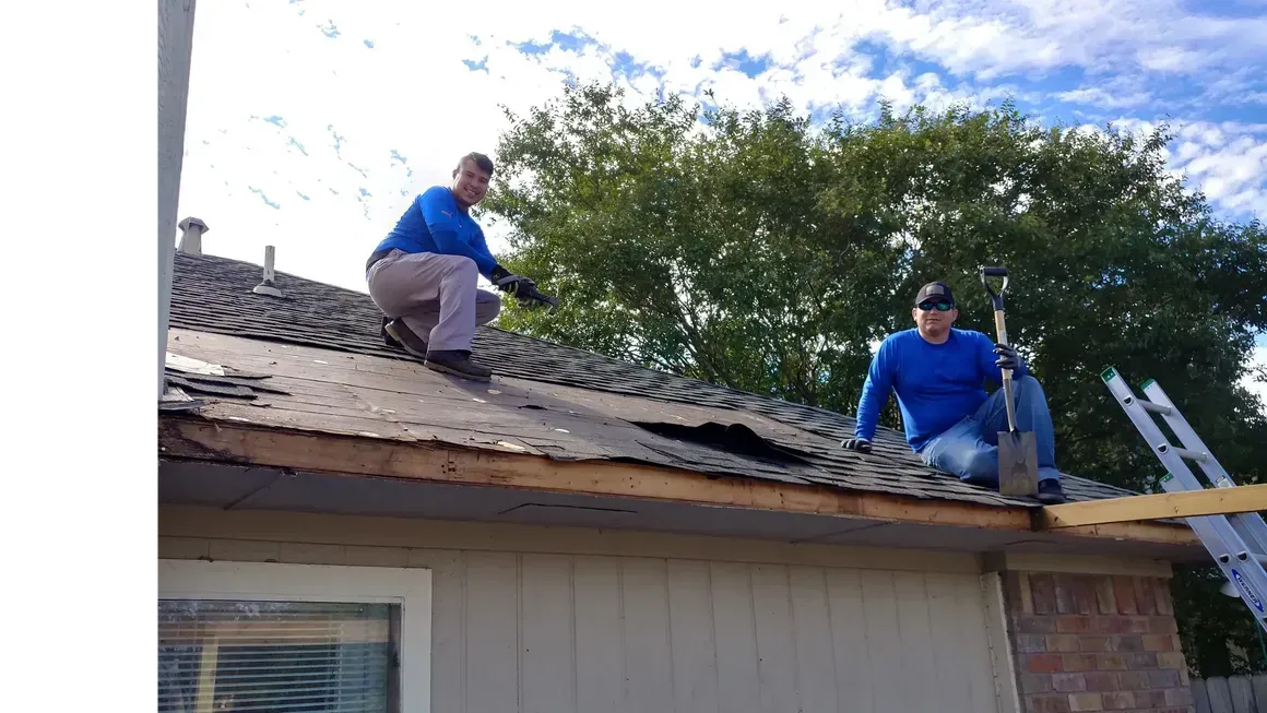 Two men are working on the roof of a house.