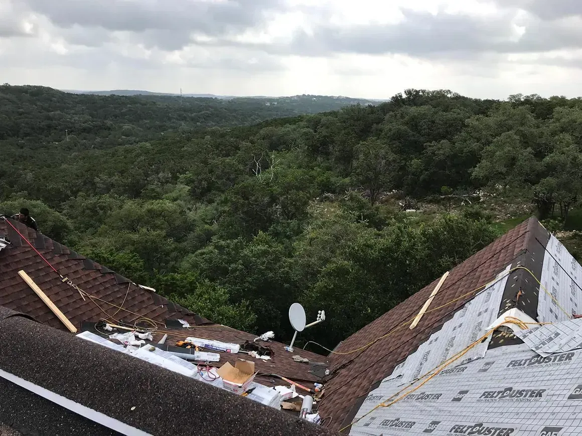 A roof with a view of a forest and a satellite dish on it.