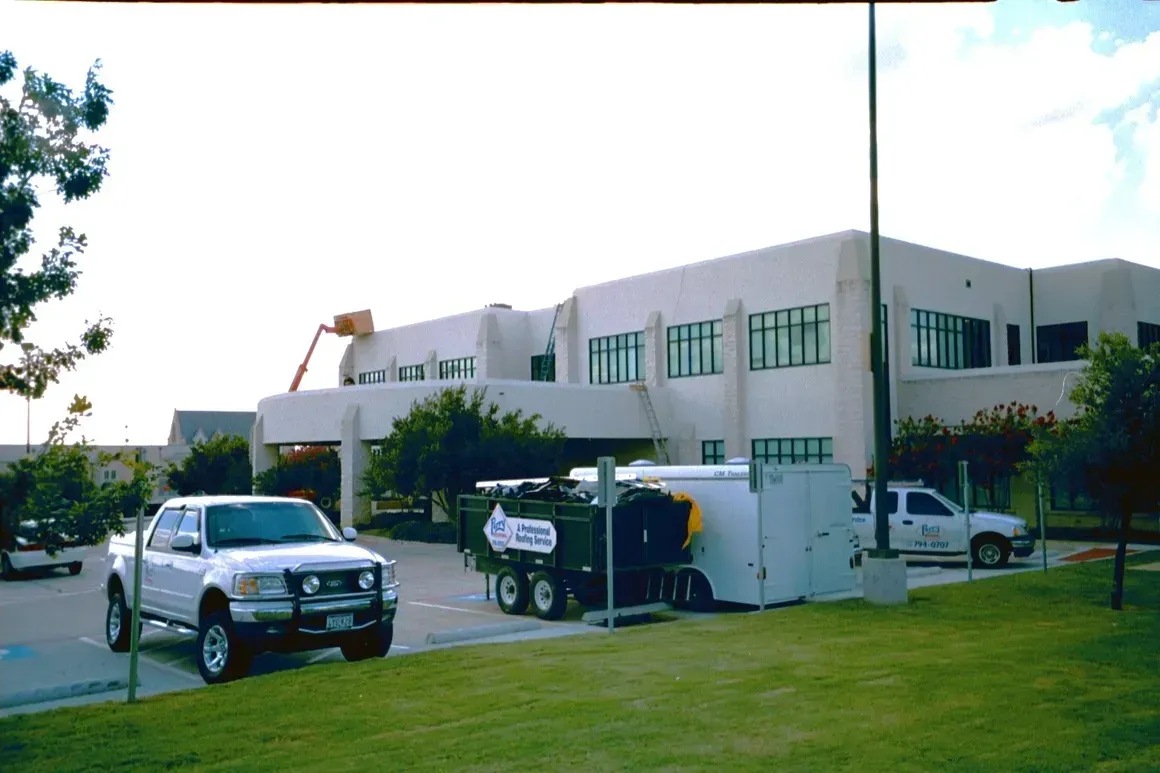 A white truck is parked in front of a large building