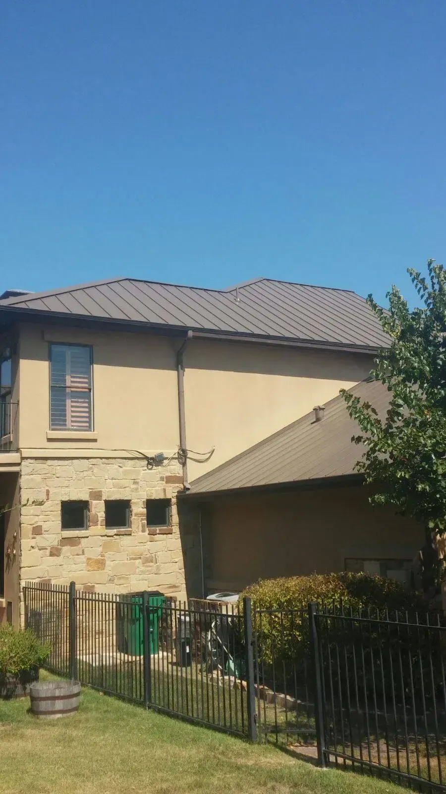 A large house with a fence in front of it and a blue sky in the background.