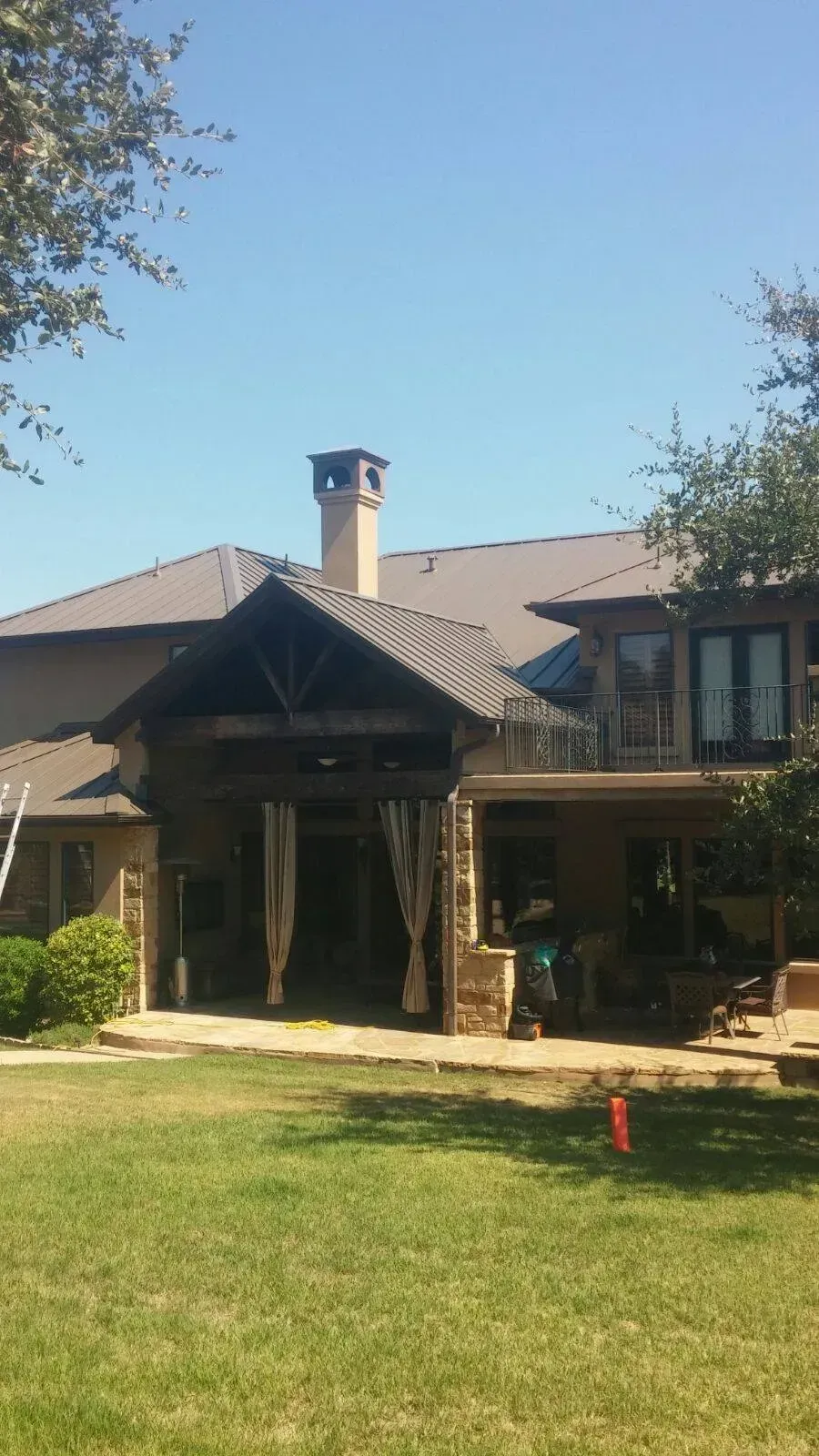 A large house with a chimney on the roof is sitting on top of a lush green lawn.