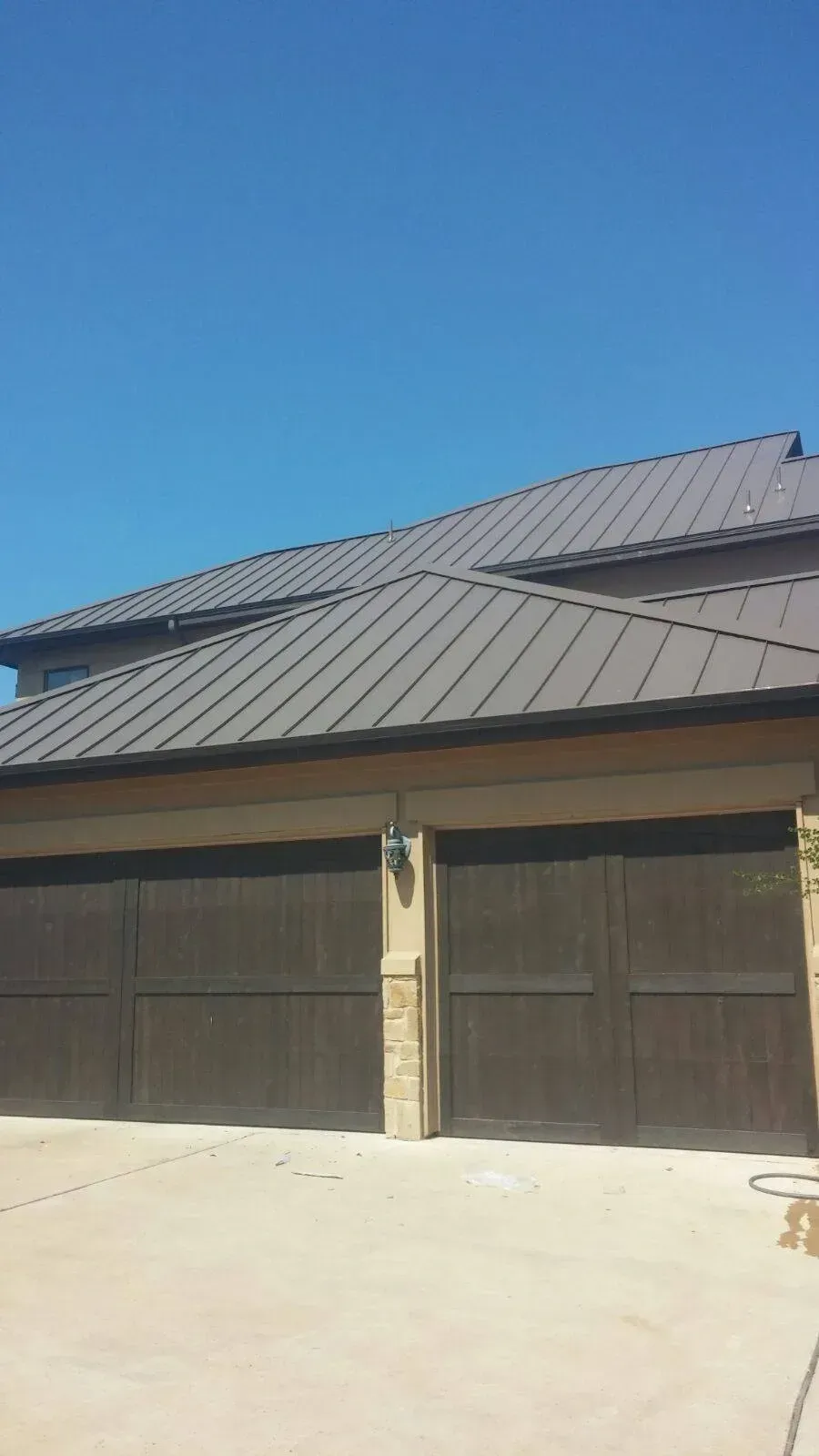 A house with two garage doors and a metal roof.
