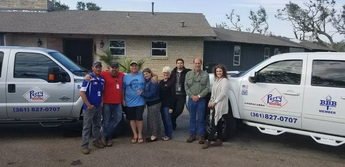 A group of people are posing for a picture in front of two trucks.