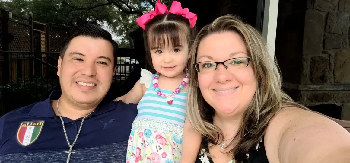 A man and woman are posing for a selfie with a little girl.