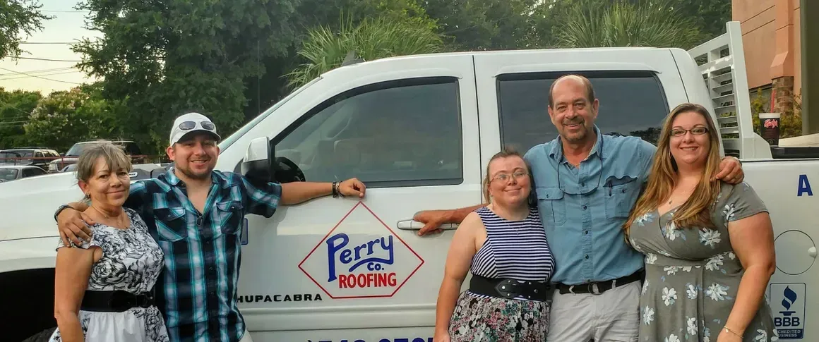 A group of people are posing for a picture in front of a truck.