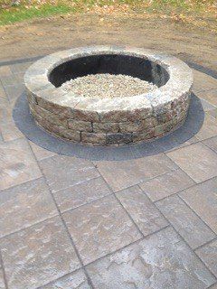 Stone fire pit on a square paved patio.