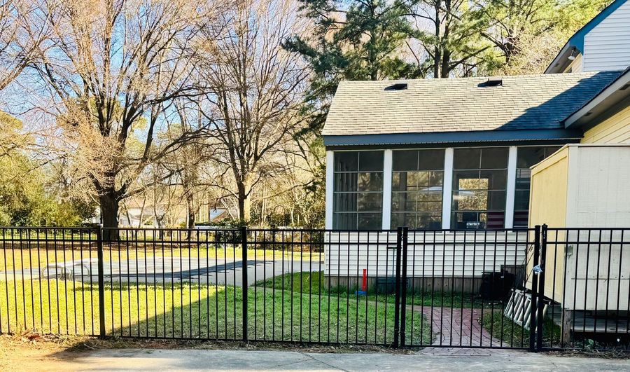 A house with a screened in porch and a black fence in front of it.