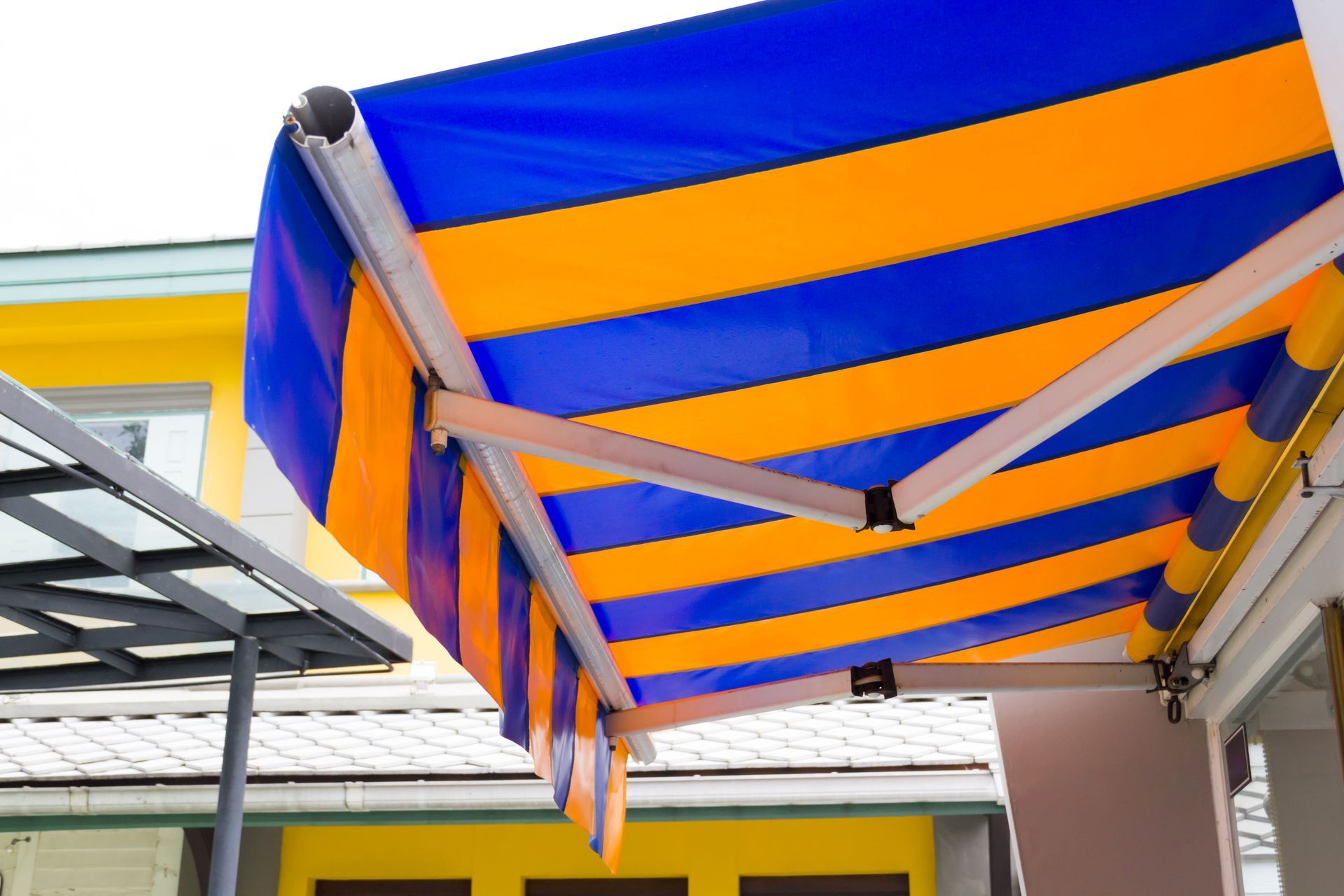 Blue-and-orange striped awning over a patio beside a yellow building