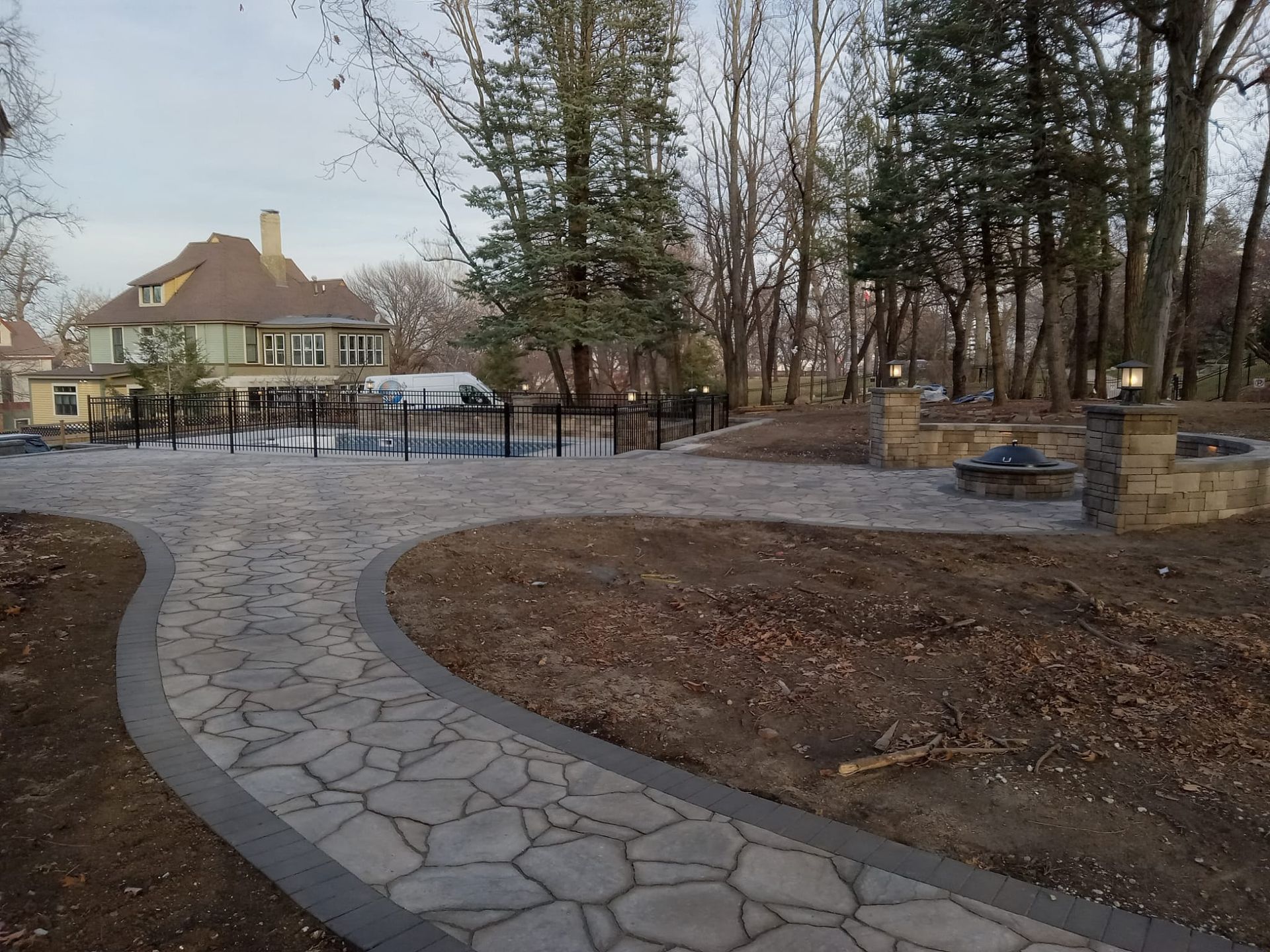 A stone walkway leading to a house surrounded by trees