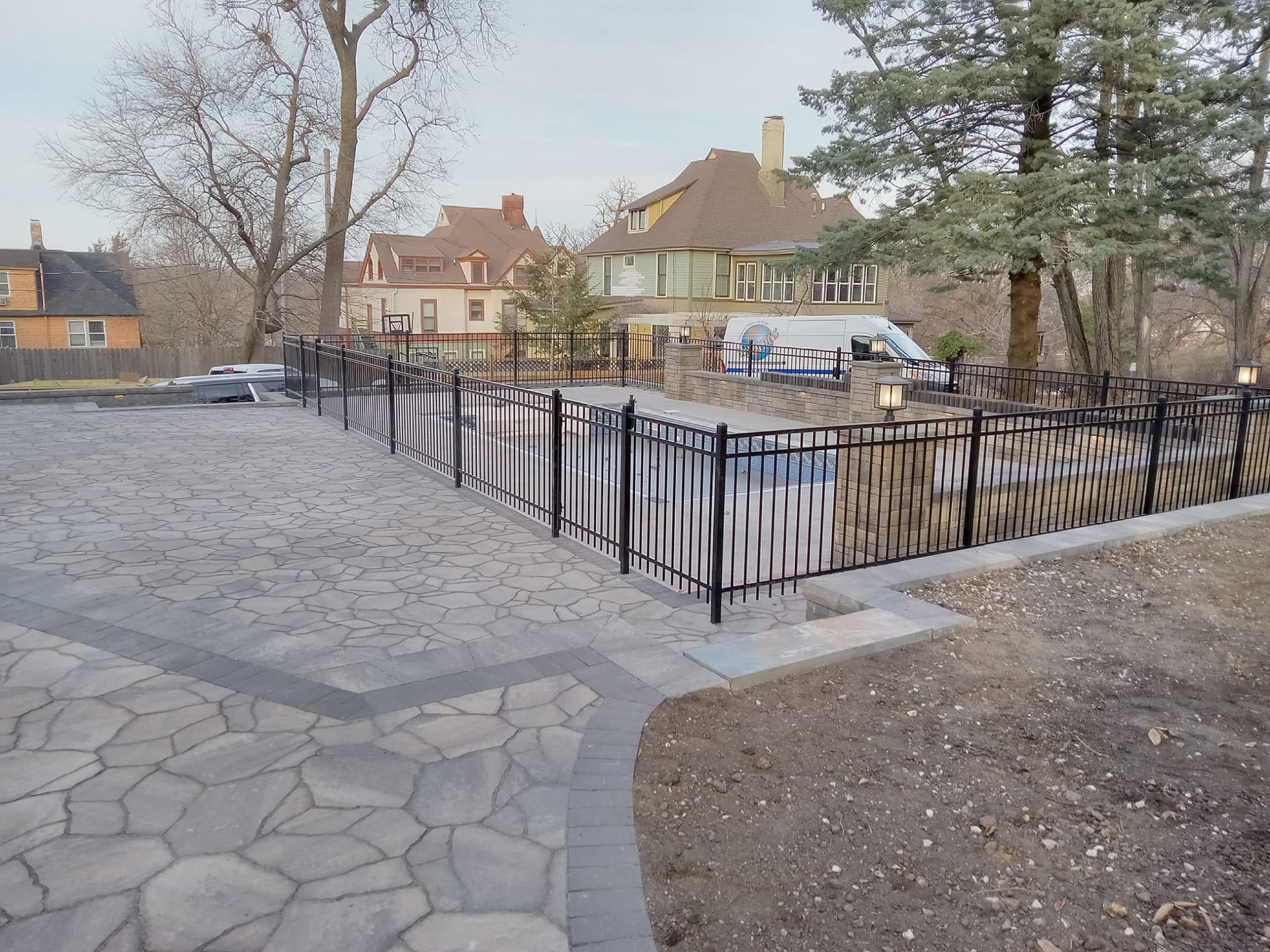 A wrought iron fence surrounds a patio area with a house in the background