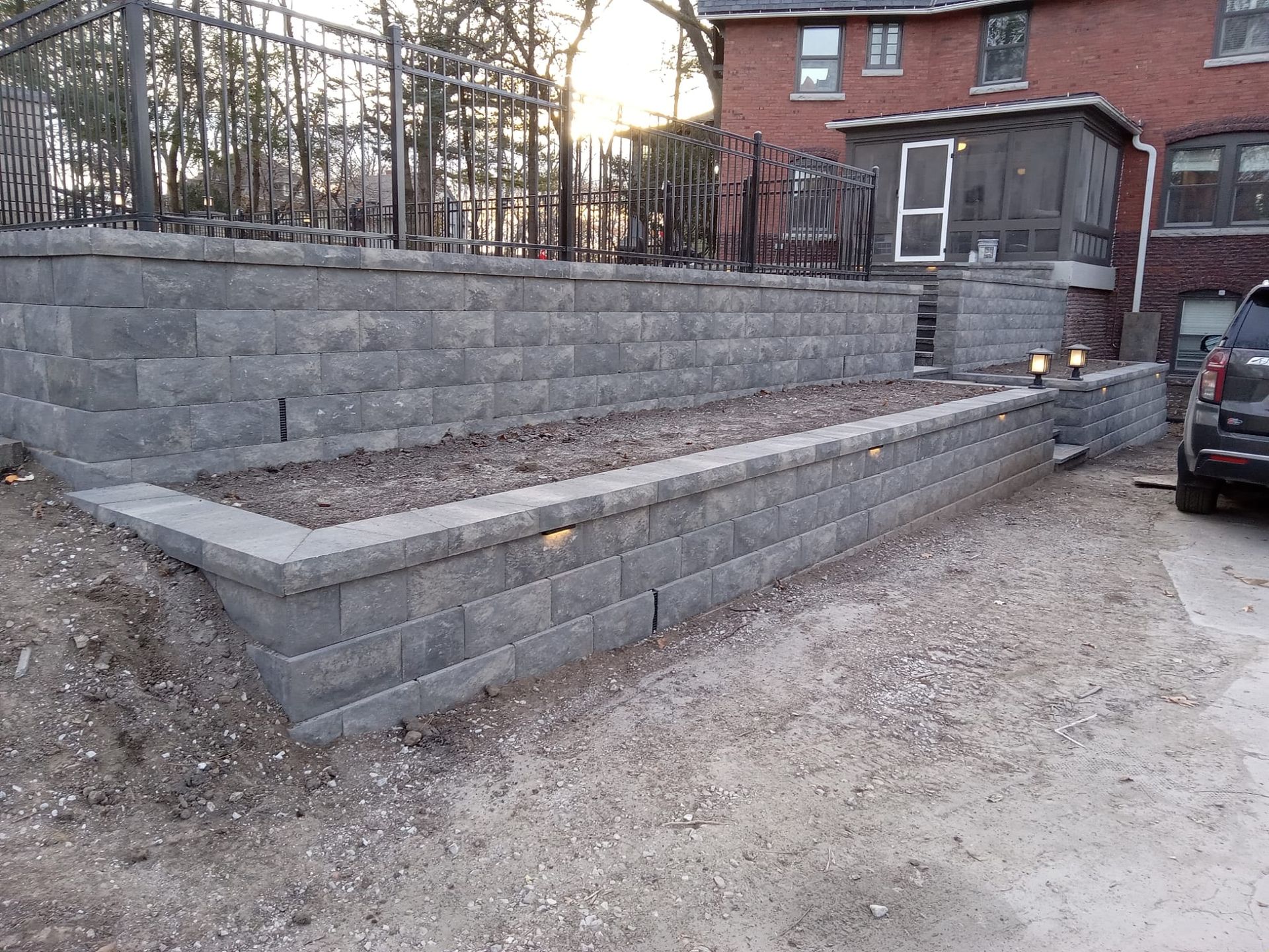 A brick wall is being built in front of a brick house