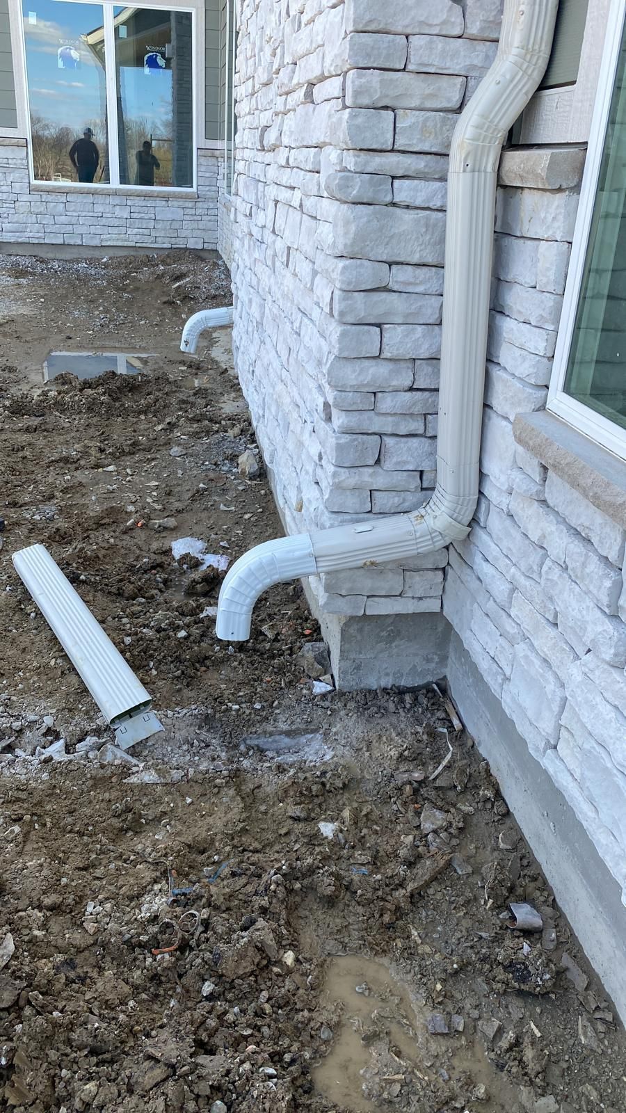A drain pipe is being installed on the side of a brick building