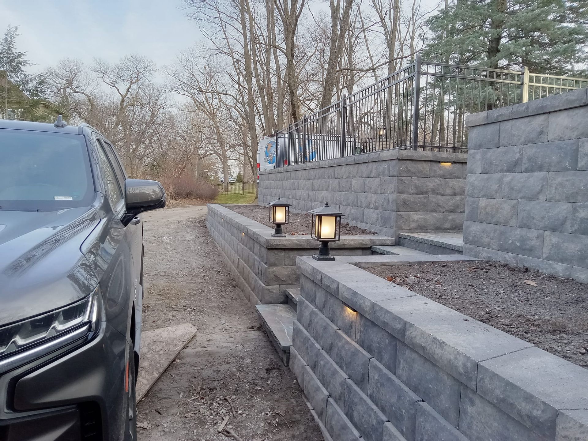 A black car is parked next to a brick wall