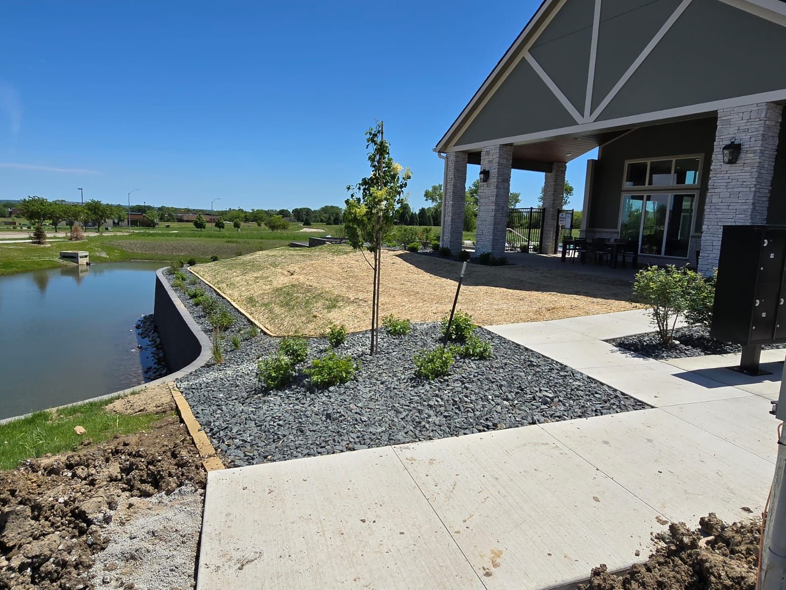 A concrete walkway leads to a building with a pond in the background