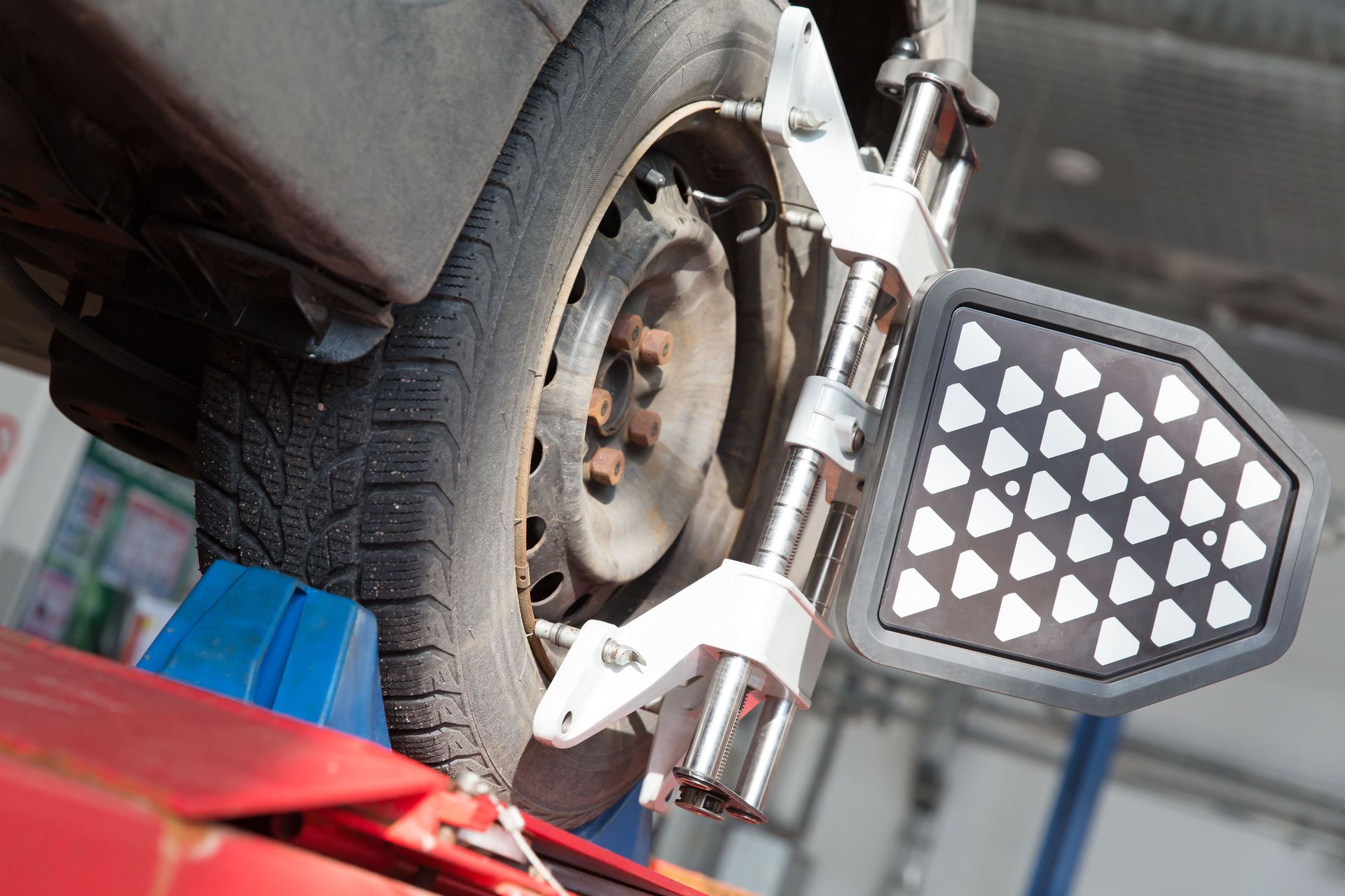 Motorcycle wheel and footpeg close-up in a garage, with a red lift beneath it