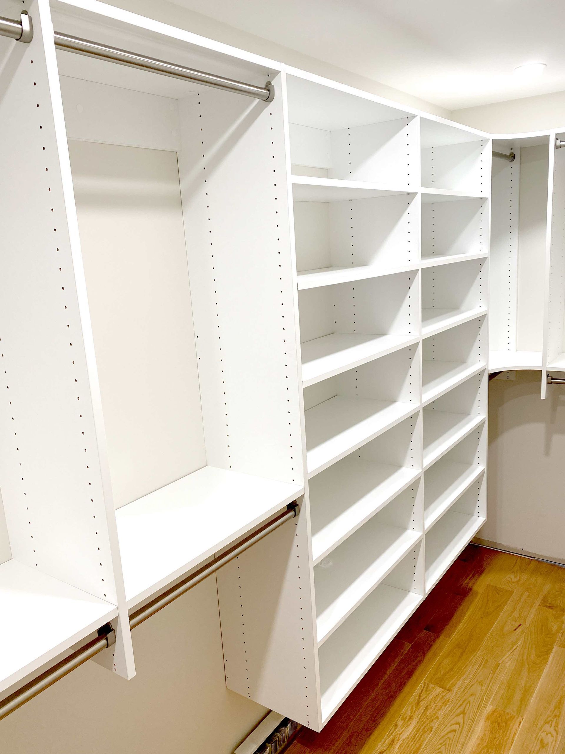 A walk in closet with lots of shelves and a wooden floor.