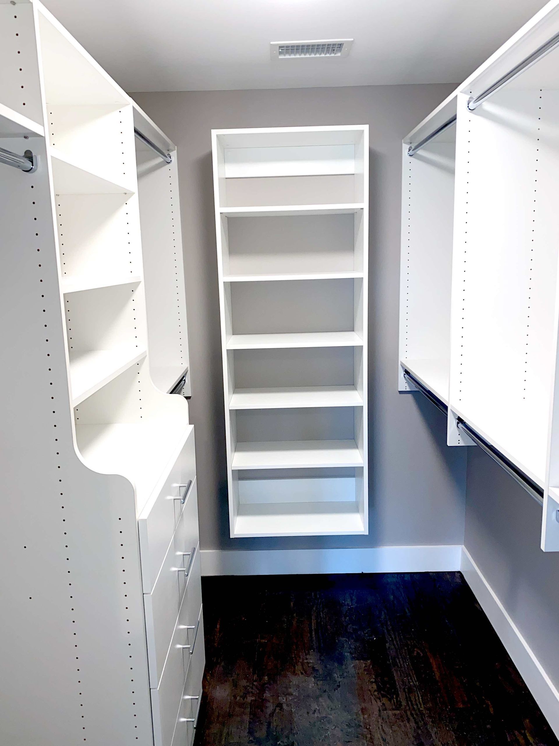 A walk in closet with lots of shelves and drawers