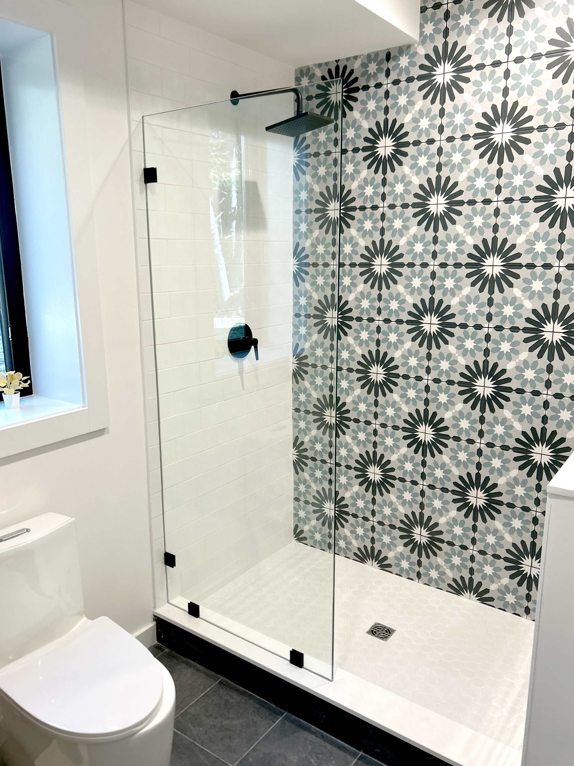 A bathroom with a walk in shower , toilet and window.