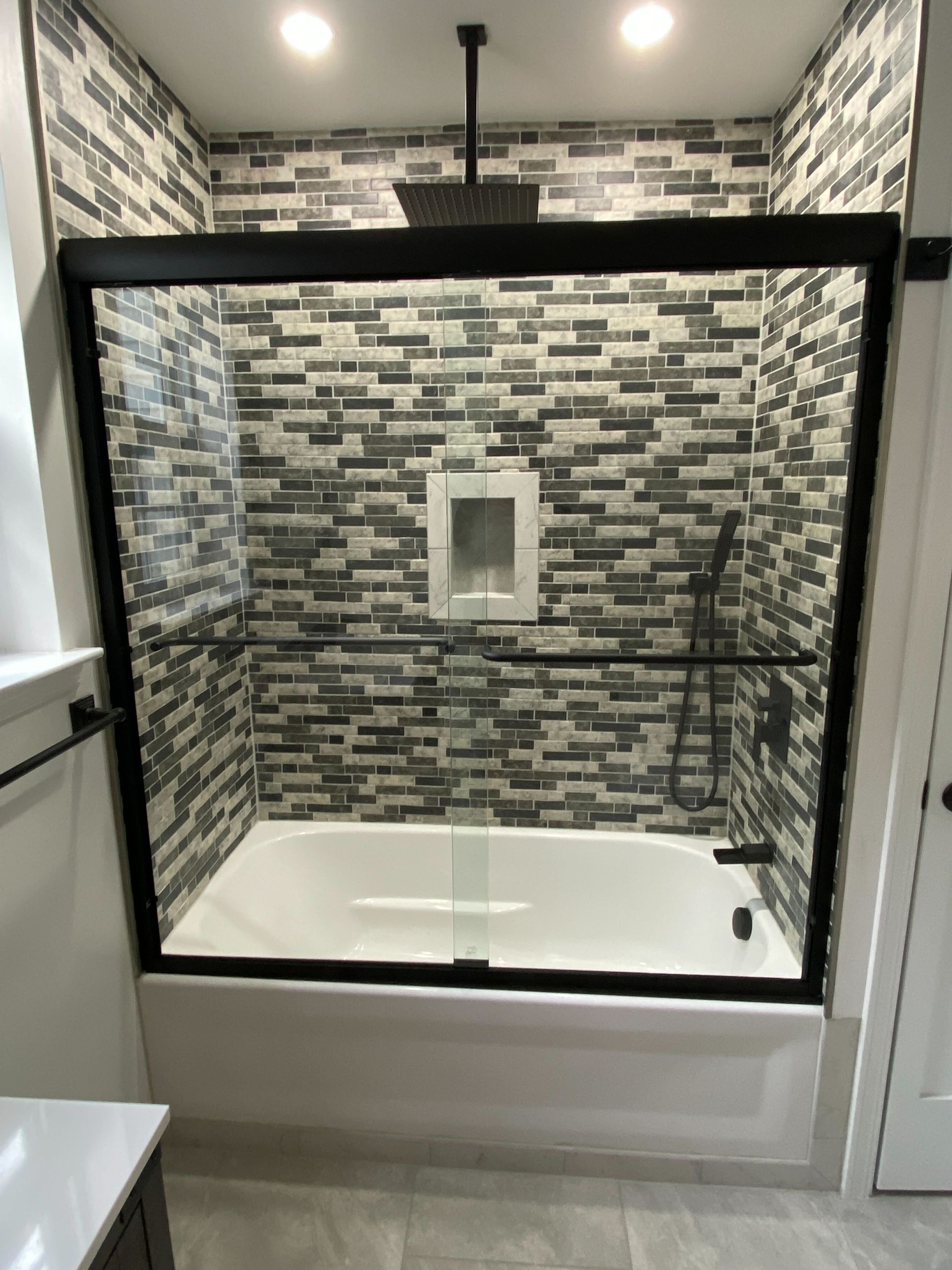 A bathroom with a bathtub and a shower with a sliding glass door.