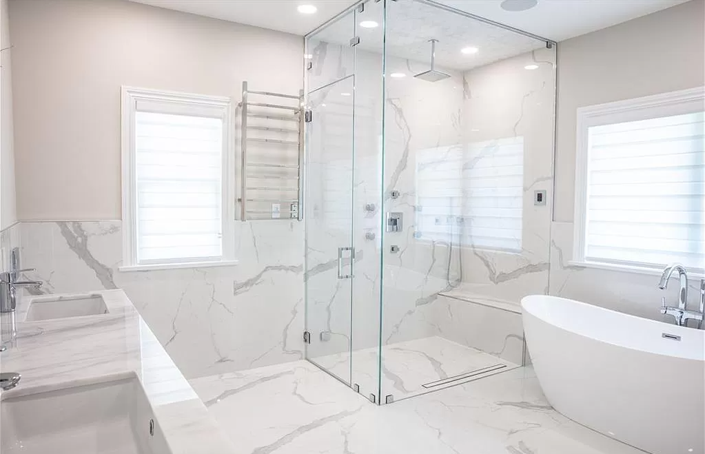 A bathroom with a walk-in shower, tub, sink and window.